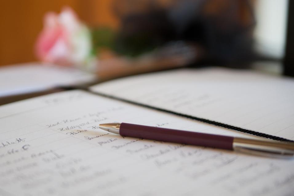 Nahaufnahme eines Notizbuchs mit handschriftlichen Notizen und einem Kugelschreiber auf einem Tisch.
